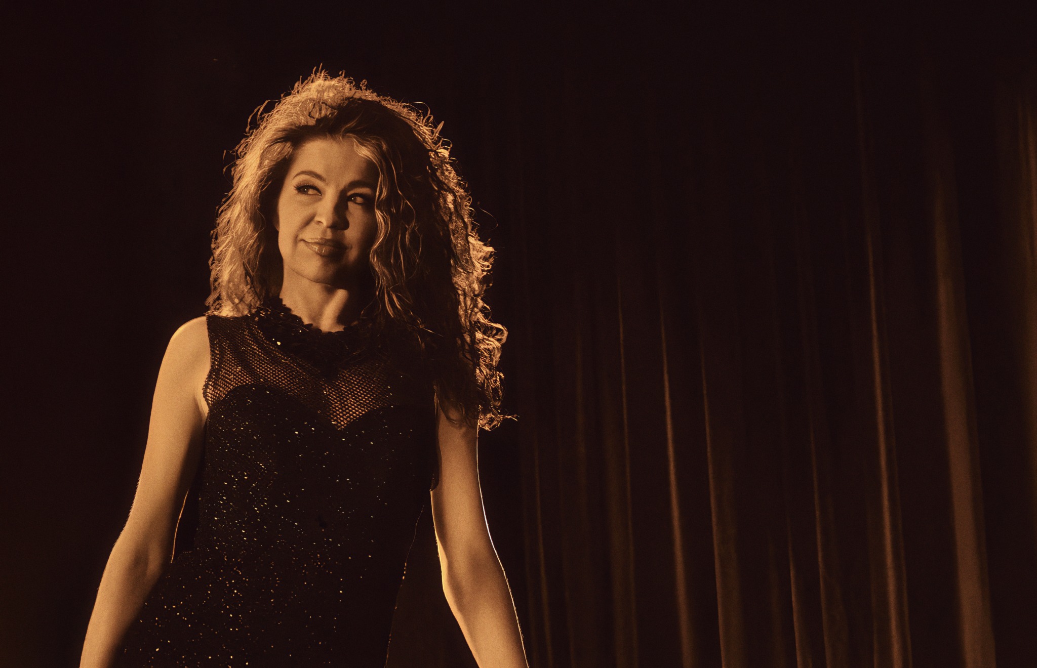 Jaimee Paul in a gold-lit stage portrait for the Bonded concert production